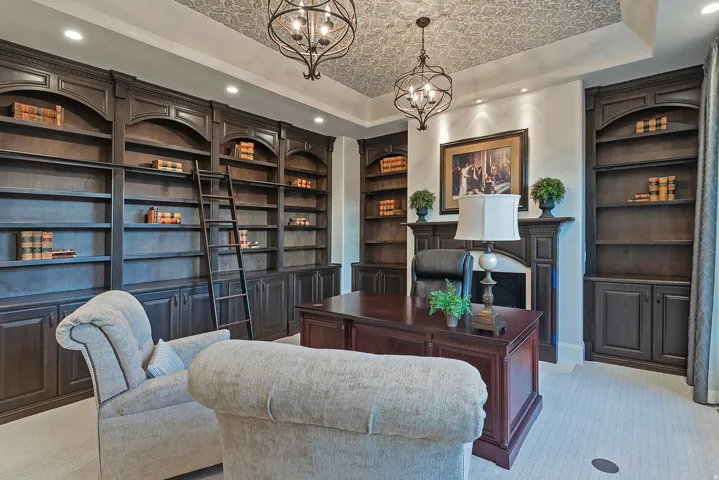 Carpeted office space featuring built in features, hanging lights, and a raised ceiling