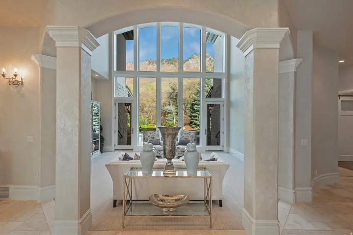 Living area featuring ornate columns, a high ceiling, light carpet, and recessed lighting