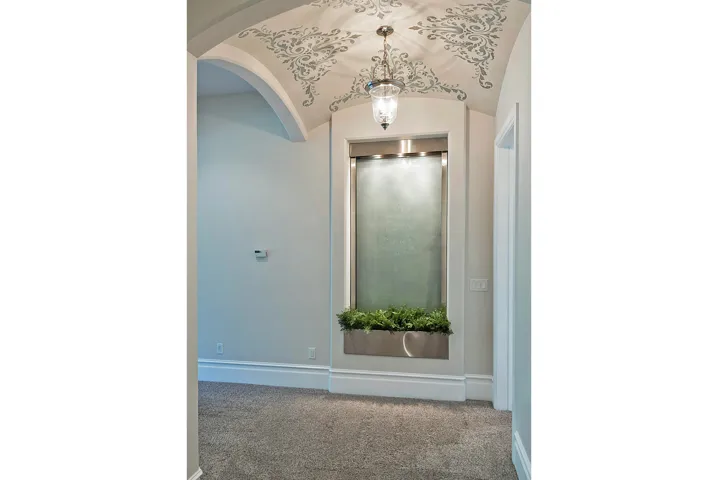 Hallway featuring carpet flooring, arched walkways, and vaulted ceiling