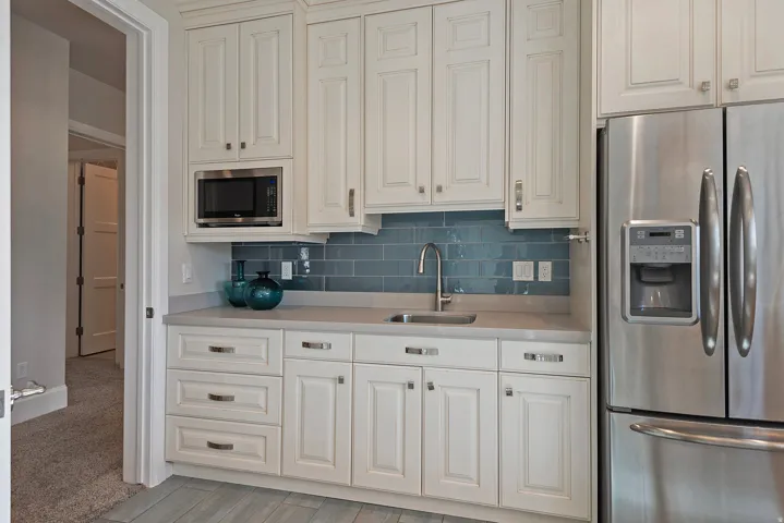 Kitchen featuring stainless steel appliances, decorative backsplash, and white cabinetry
