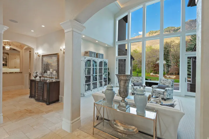 Living area featuring arched walkways, a high ceiling, decorative columns, and stone tile flooring