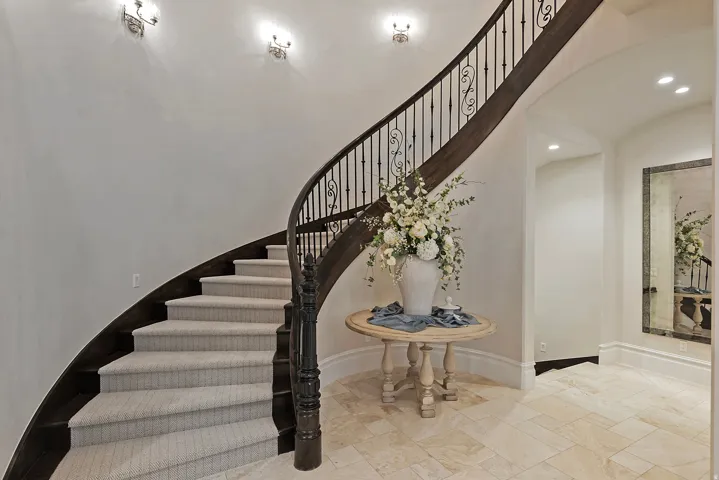 Stairs with recessed lighting, stone tile flooring, and arched walkways