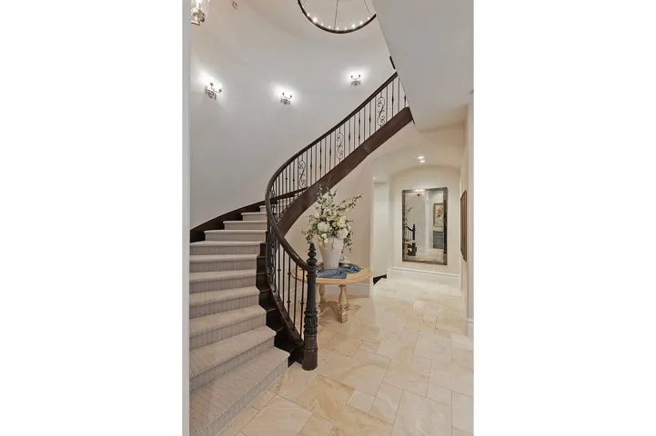 Stairway featuring arched walkways, a chandelier, stone finish flooring, and a high ceiling