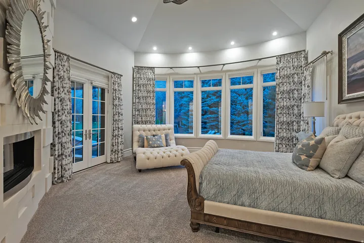 Carpeted bedroom with access to exterior, a tiled fireplace, recessed lighting, lofted ceiling, and french doors