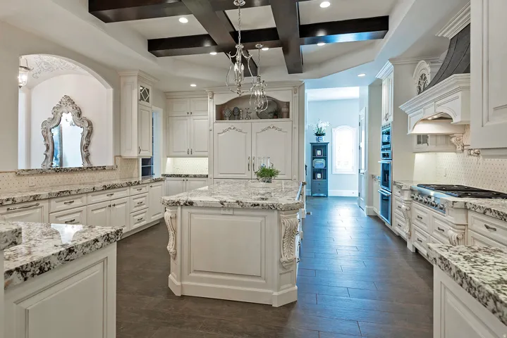 Kitchen with decorative backsplash, coffered ceiling, dark wood-type flooring, light stone counters, and a kitchen island