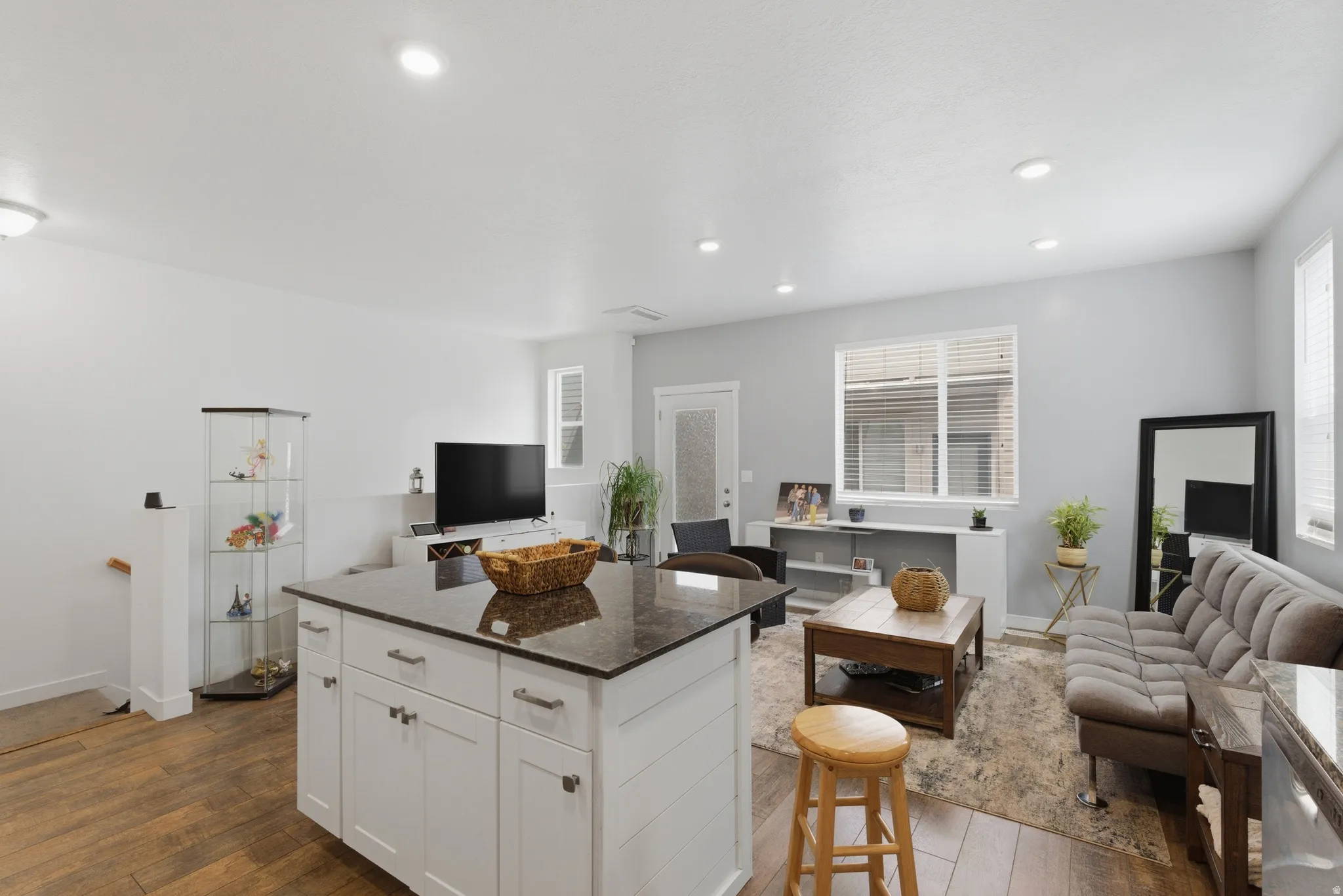 Kitchen featuring open floor plan, a kitchen bar, a kitchen island, dark stone counters, and recessed lighting