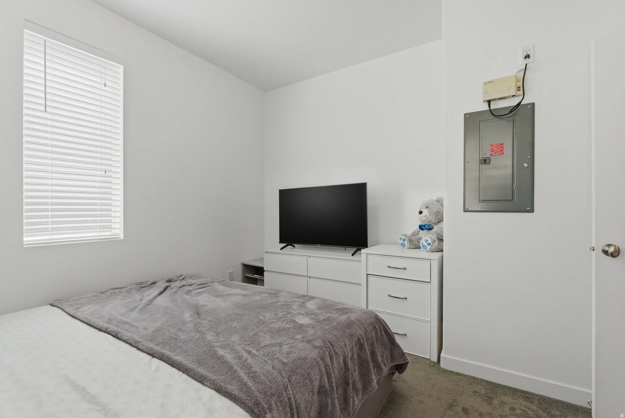 Bedroom featuring electric panel and dark colored carpet