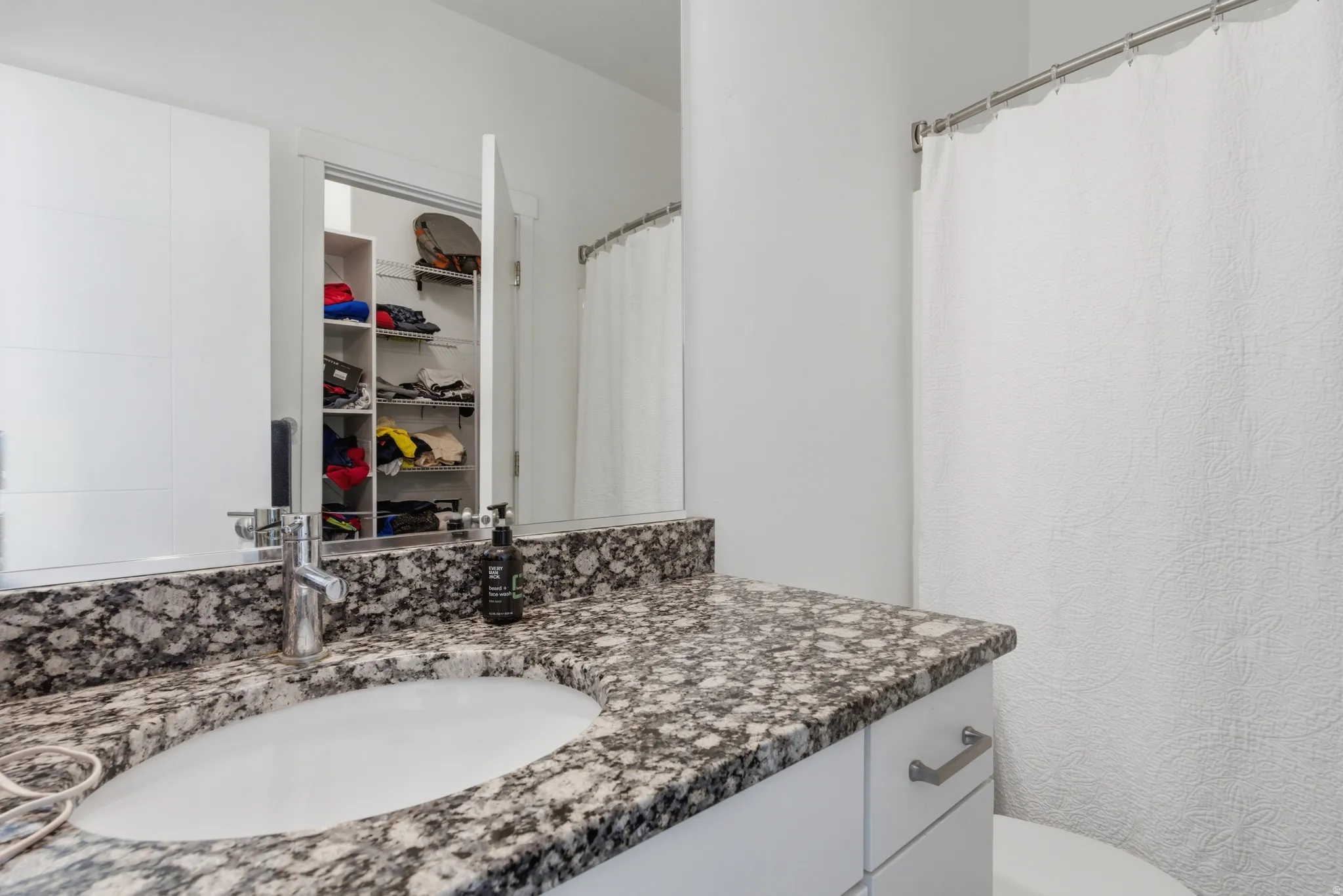 Full bath with vanity, a shower with shower curtain, and a spacious closet