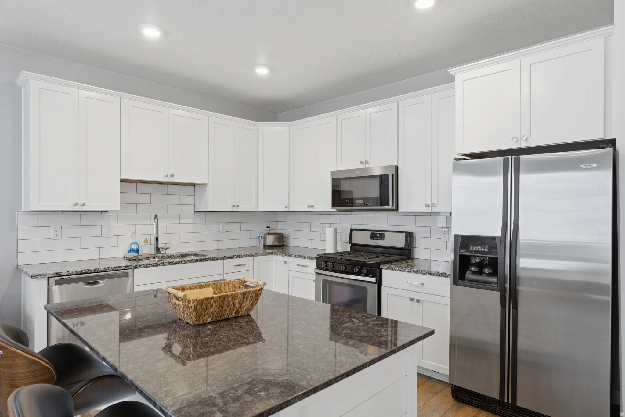 Kitchen with stainless steel appliances, dark stone counters, a breakfast bar, backsplash, and a center island