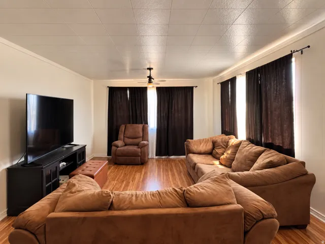 Hardwood flooring throughout, crown molding, ceiling fan, and multiple windows