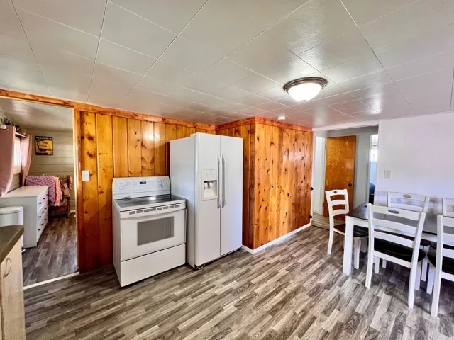 Kitchen featuring white appliances, dark wood finished floors, and wood walls