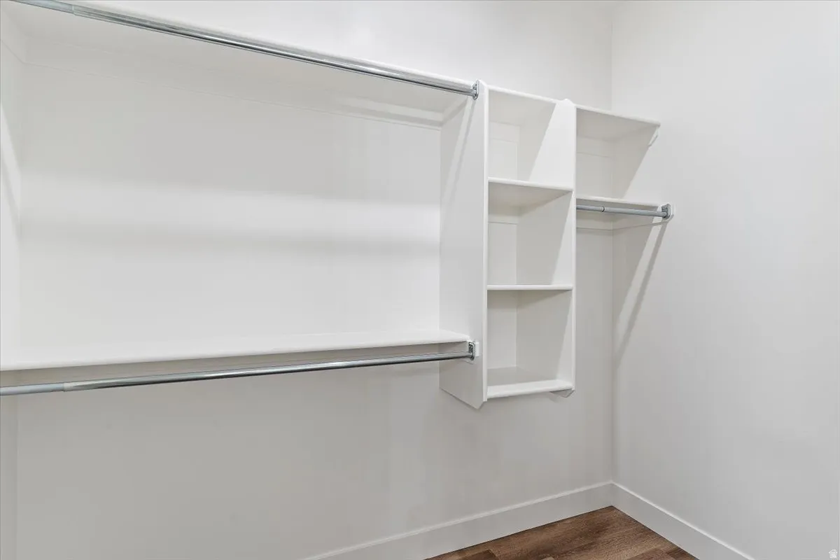 Walk in closet with dark wood finished floors