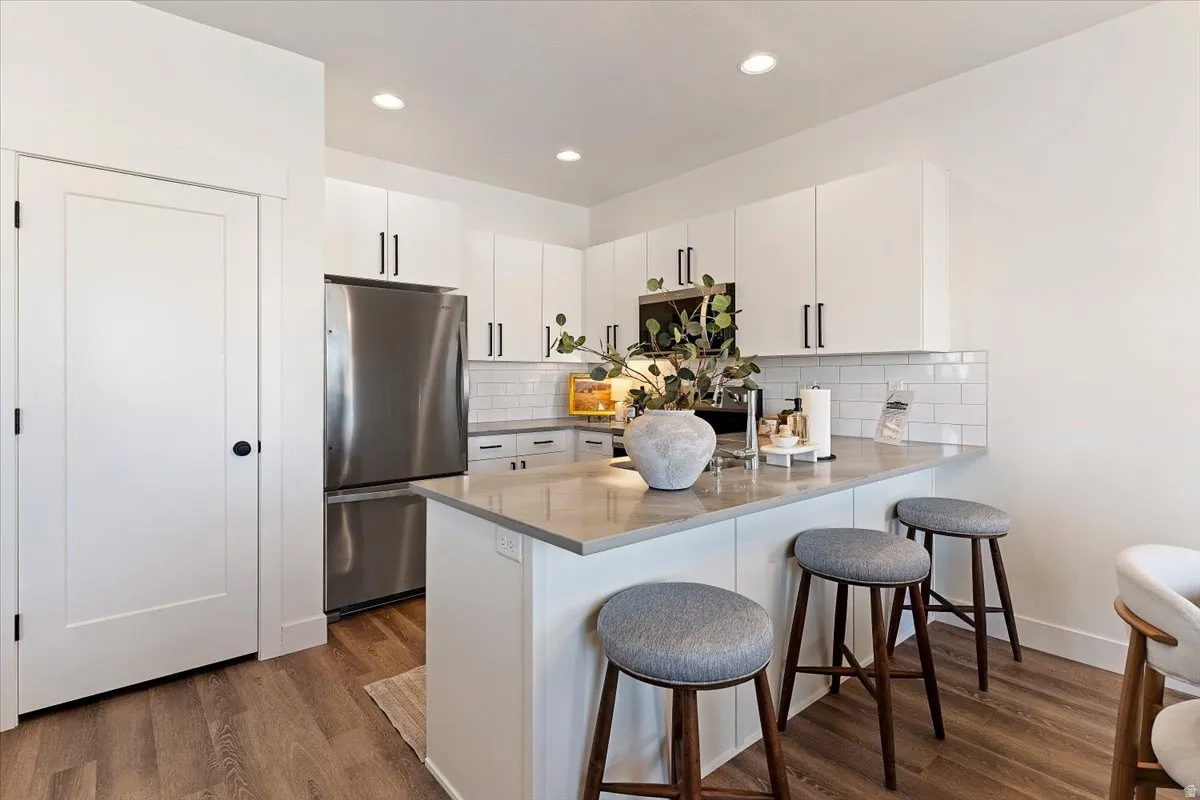 Kitchen featuring white cabinetry, a breakfast bar area, stainless steel appliances, a peninsula, and dark wood finished floors