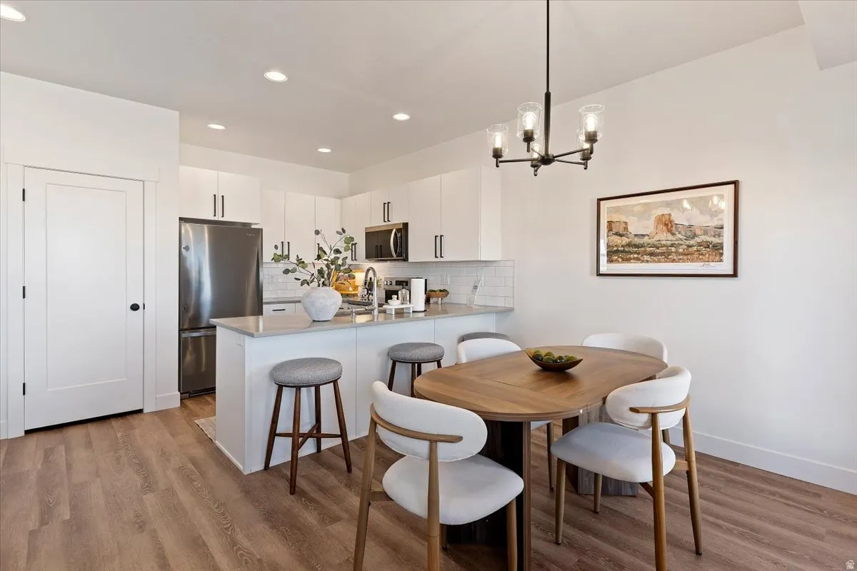 Dining area with light wood-style flooring and suspended lighting