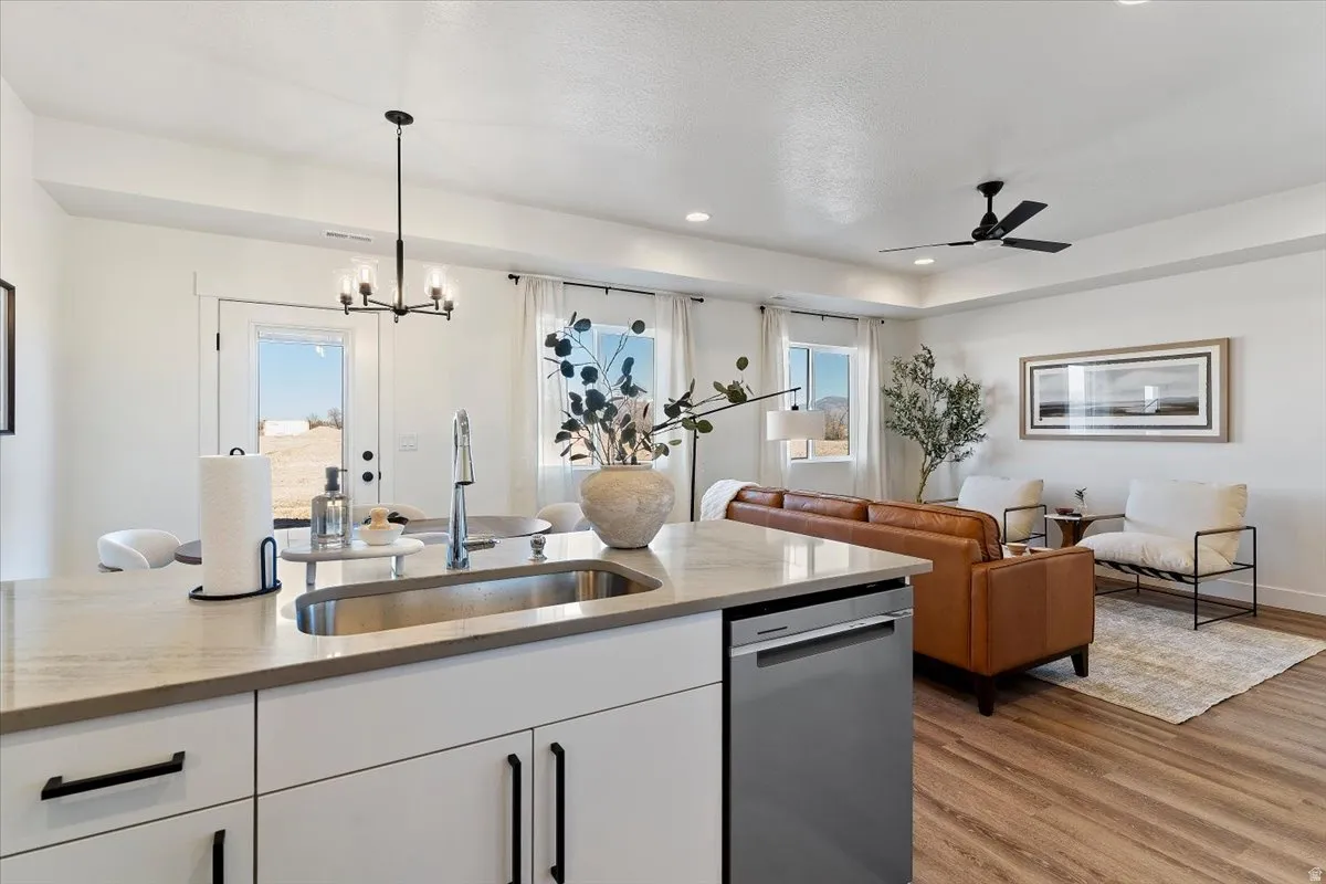 Kitchen featuring white cabinetry, light stone countertops, stainless steel dishwasher, and open floor plan