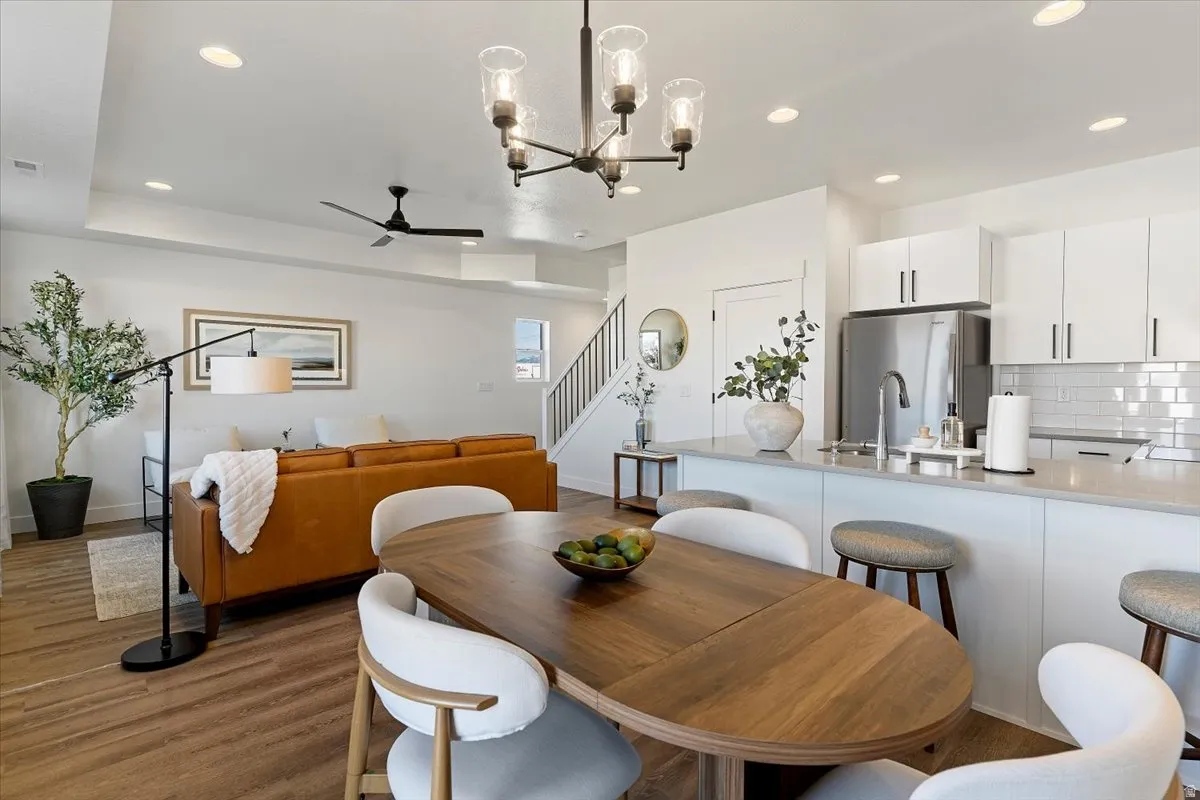 Dining space with suspended lighting, ceiling fan, and dark wood-style floors