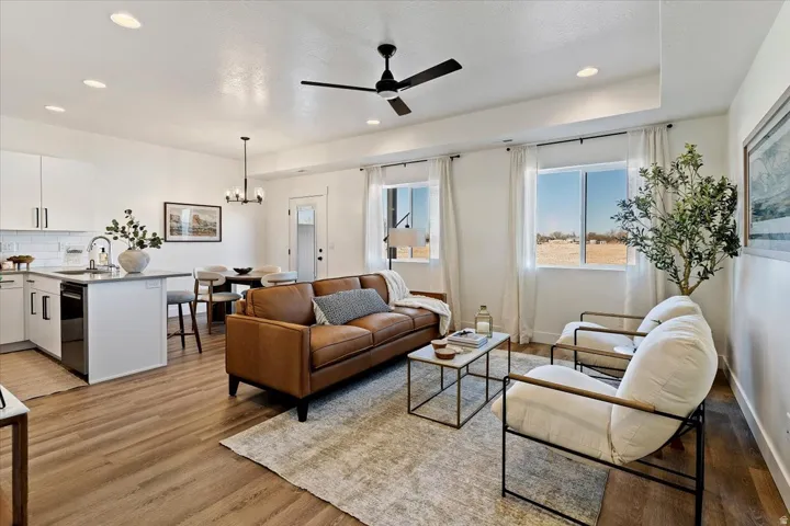 Living area featuring a ceiling fan, suspended lighting, and light wood-type flooring