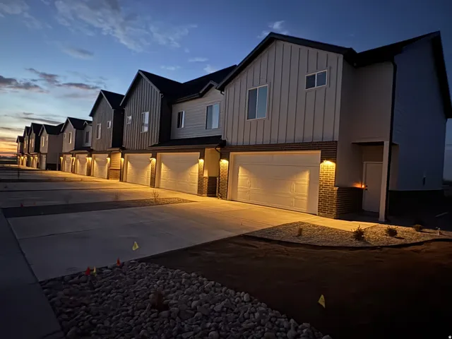 Modern inspired farmhouse with board and batten siding, an attached garage, brick siding, and concrete driveway