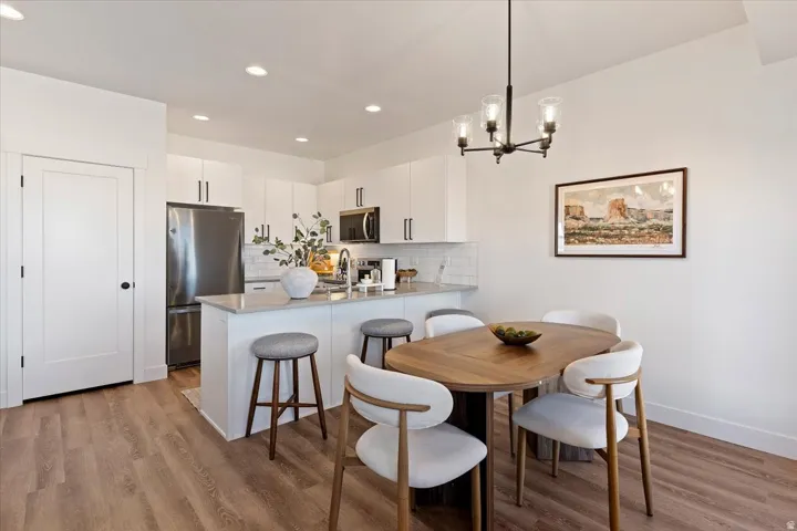 Dining area with light wood-style flooring and suspended lighting