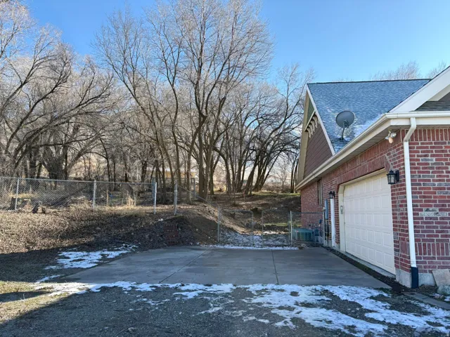 View of property exterior with brick siding, roof with shingles, and an attached garage