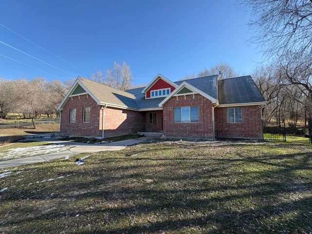 View of front of house featuring brick siding, a shingled roof, and a front yard