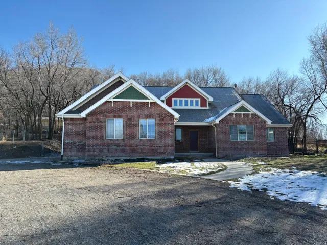 View of front facade featuring brick siding, covered porch, and a shingled roof