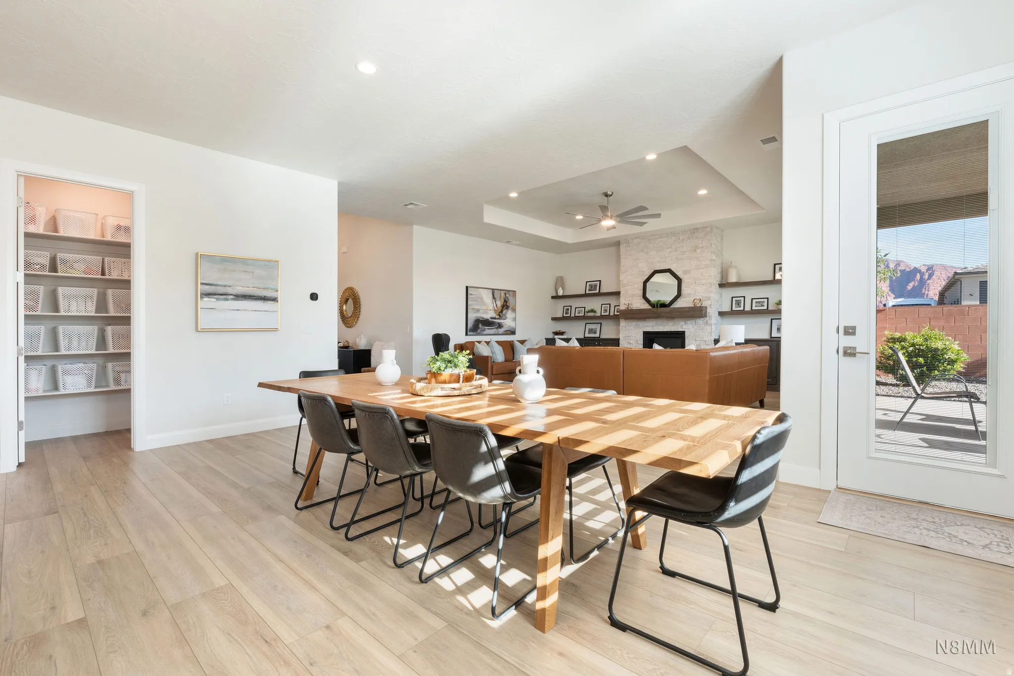 Dining space featuring light wood-style flooring, a fireplace, a tray ceiling, ceiling fan, and recessed lighting