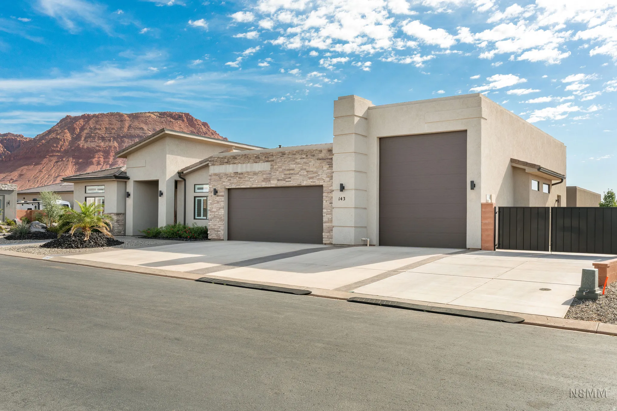 View of front facade featuring a garage, stucco siding, stone siding, and driveway