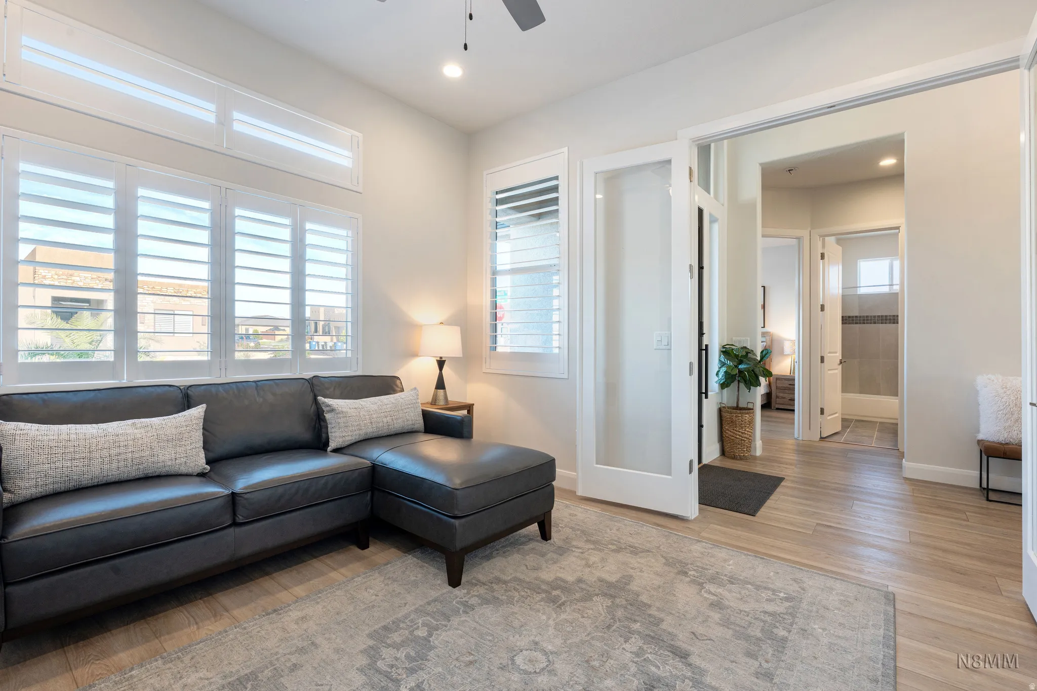 Living area with light wood-style flooring, ceiling fan, and recessed lighting