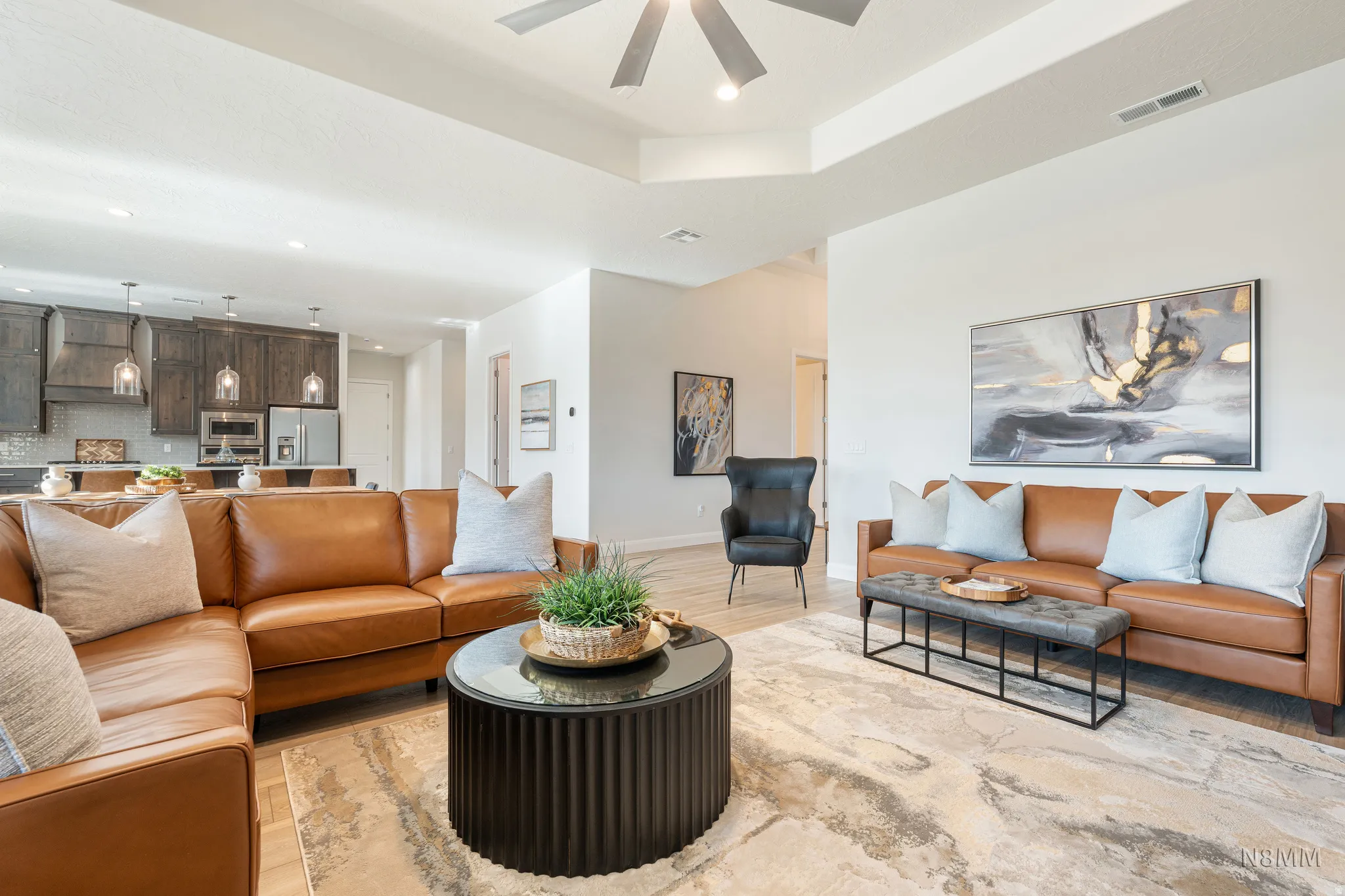 Living area featuring light wood-type flooring, recessed lighting, a ceiling fan, and a tray ceiling