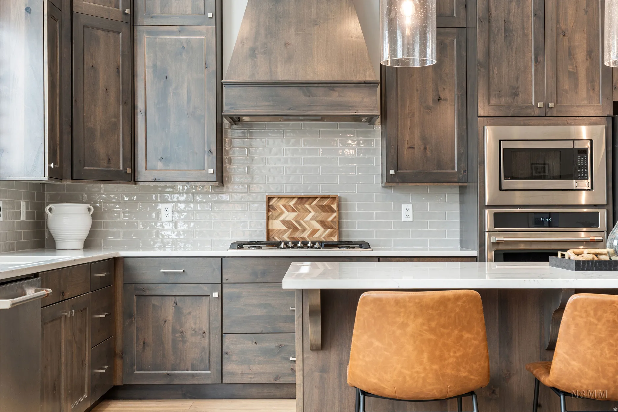 Kitchen with dark wood finish cabinets, backsplash, stainless steel appliances, and light stone counters