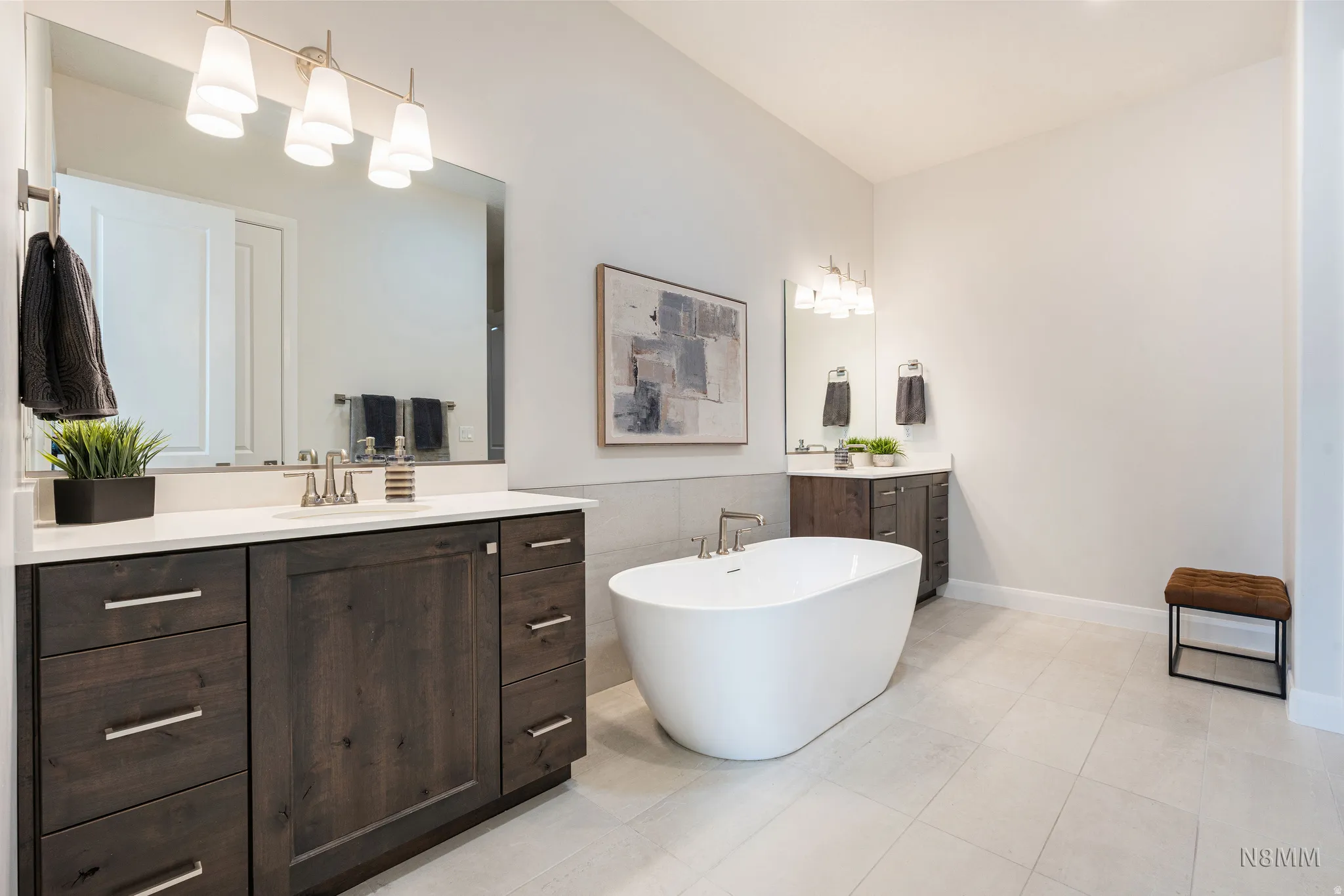Bathroom with two vanities, a freestanding bath, tile walls, and light tile patterned floors