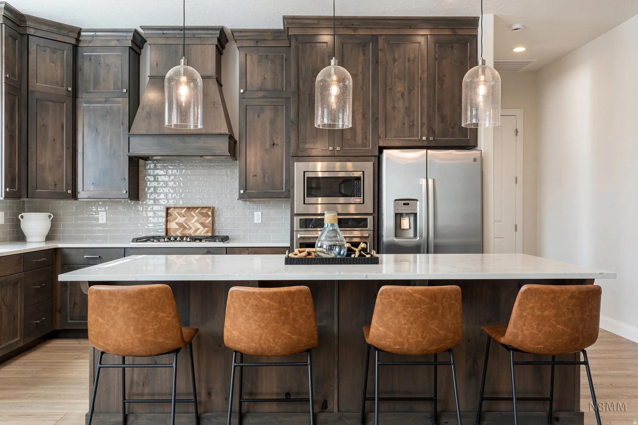Kitchen with dark wood finish cabinets, light wood-type flooring, stainless steel appliances, and a center island