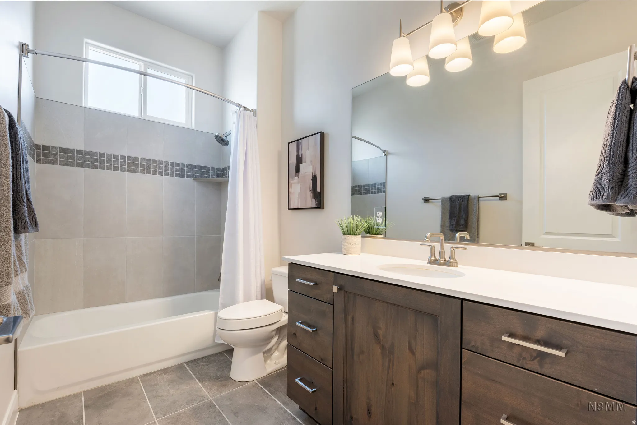 Full bath with vanity, dark tile patterned flooring, and shower / bath combo with shower curtain