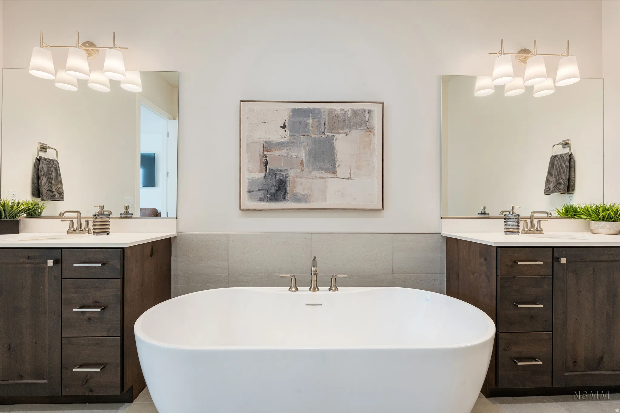 Bathroom with tile walls, two vanities, wainscoting, a freestanding bath, and suspended lighting