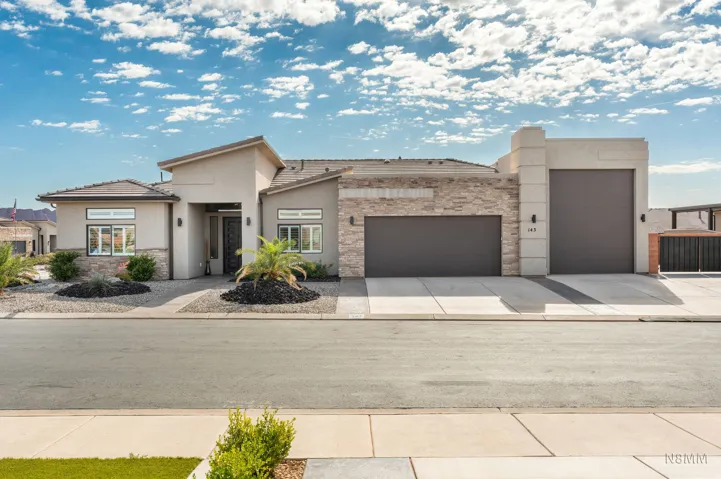 View of front of home featuring a garage, stone siding, stucco siding, and driveway