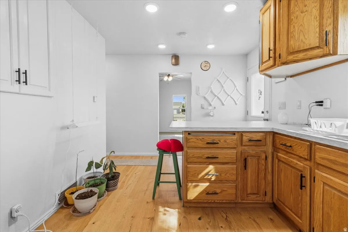 Kitchen with light countertops, wood finish cabinets, light wood finished floors, a breakfast bar, and recessed lighting