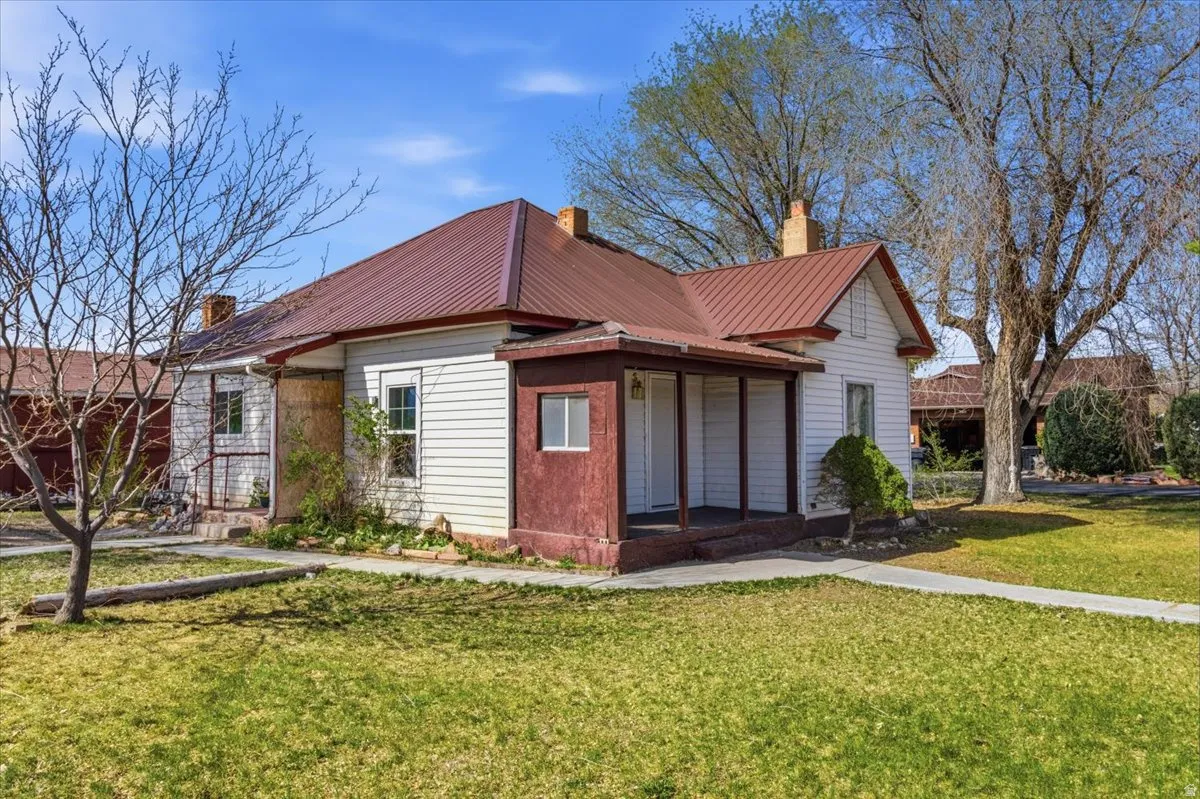 View of front of house with a front yard, a metal roof, a chimney, and a porch
