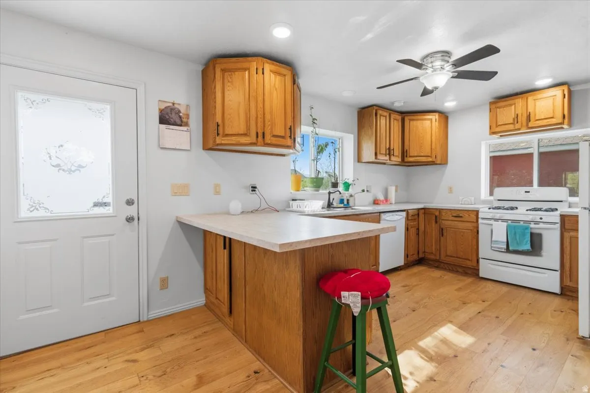 Kitchen with wood finish cabinetry, light countertops, a peninsula, a breakfast bar, and recessed lighting