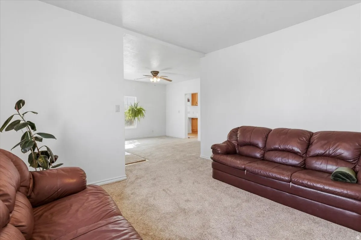 Living area with light carpet and ceiling fan