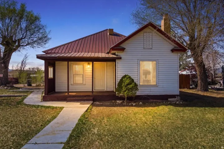 Bungalow-style house featuring a metal roof, a porch, and a lawn