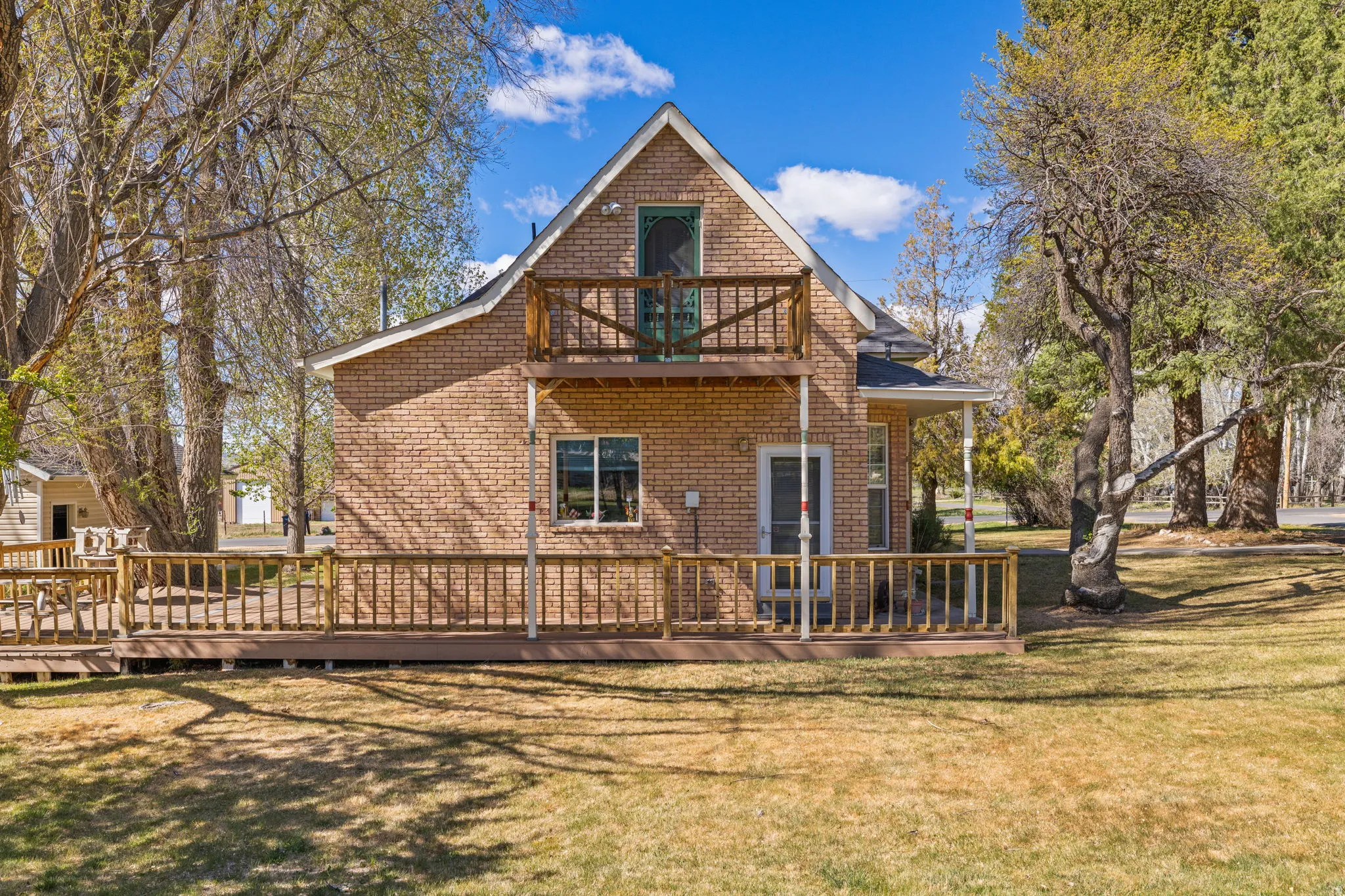 Back of house featuring a yard, a wooden deck, and brick siding