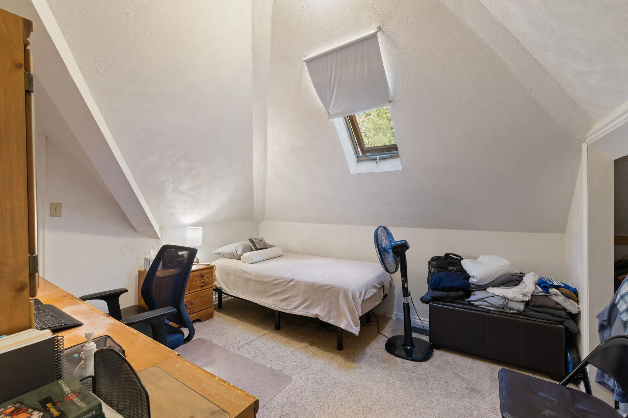 Bedroom featuring a skylight, light carpet, a desk, and lofted ceiling