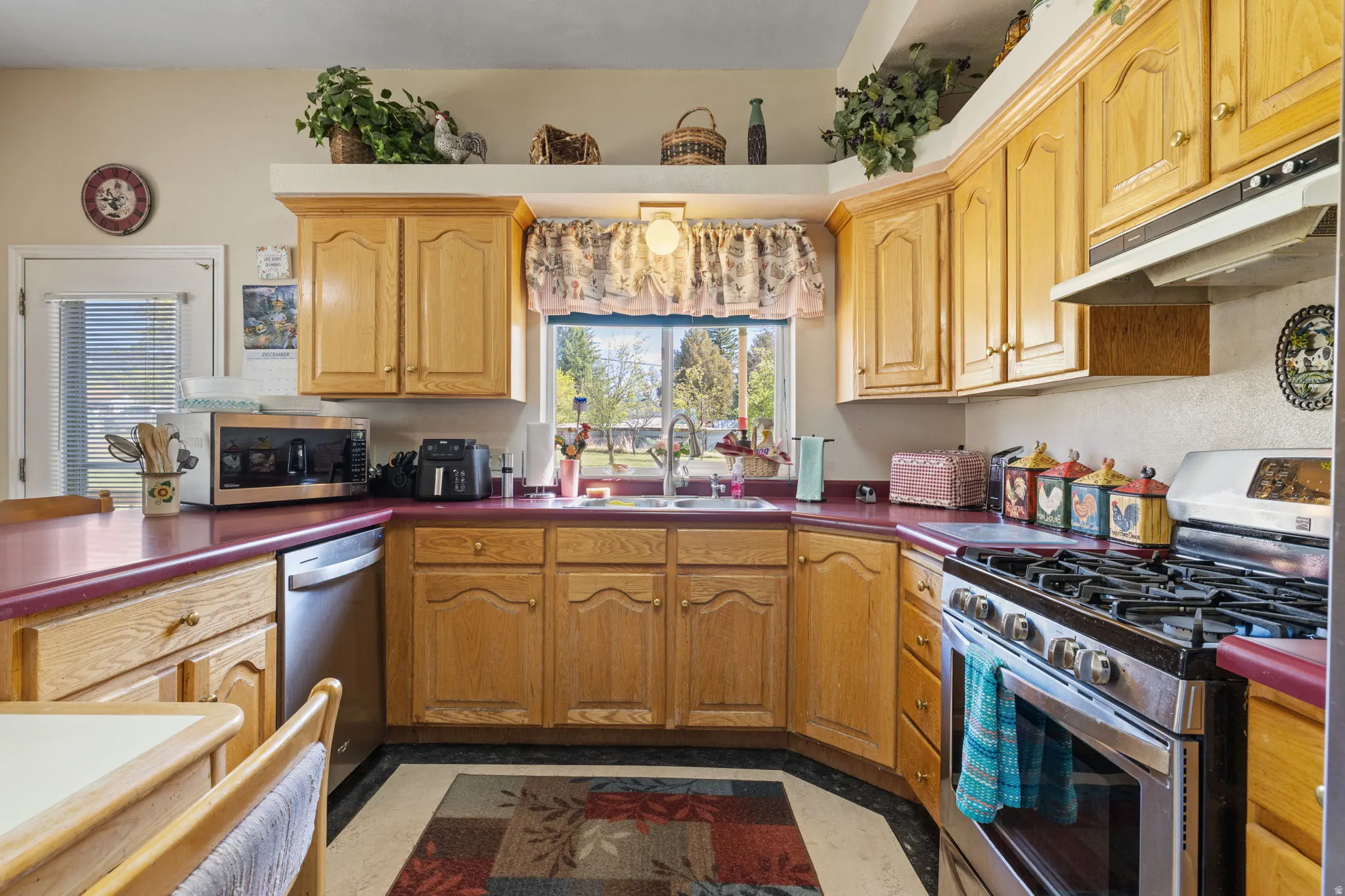 Country style kitchen with stainless steel appliances, accent brick wall and ample lighting