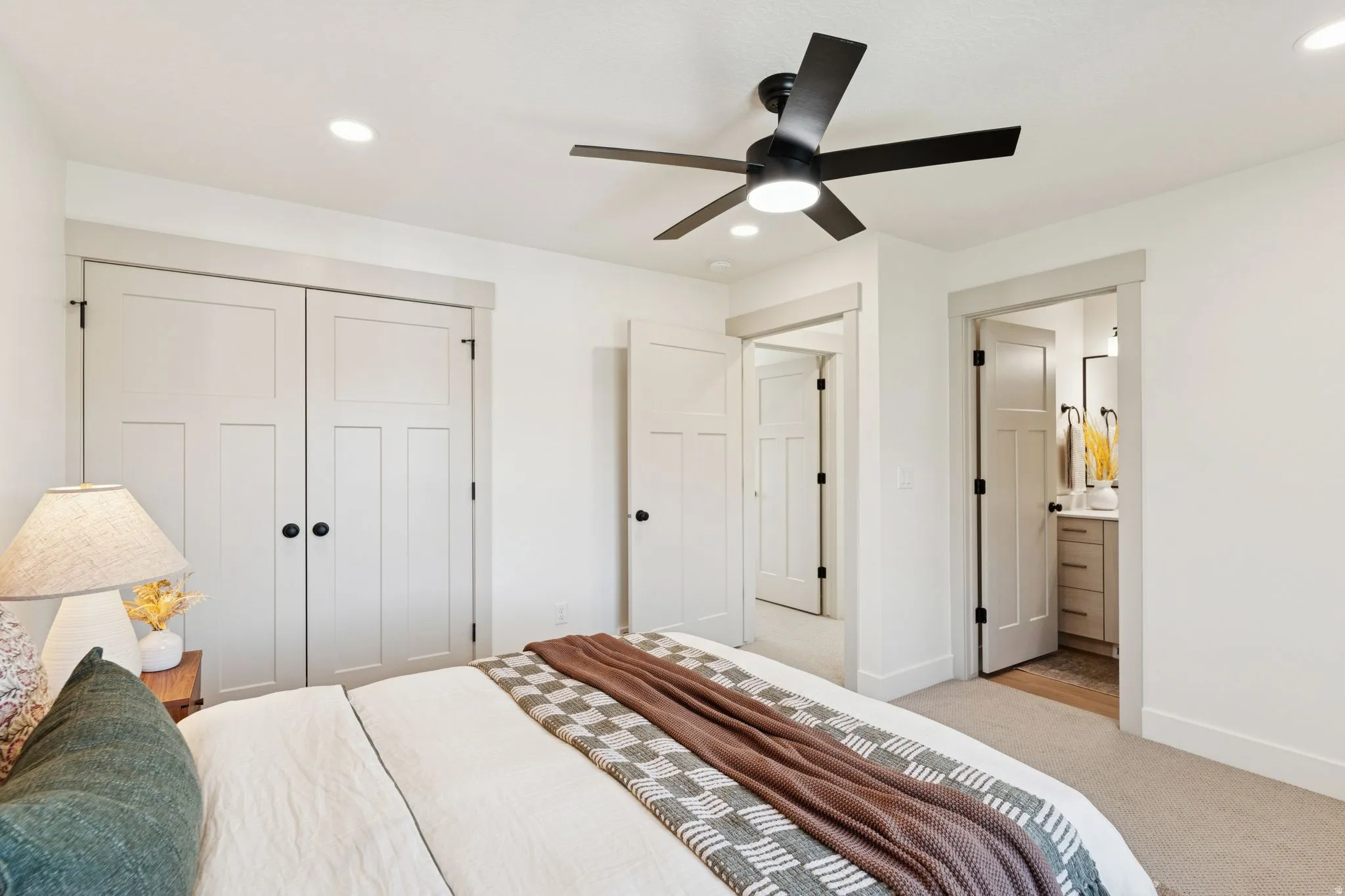 Bedroom featuring a closet, light carpet, ceiling fan, connected bathroom, and recessed lighting