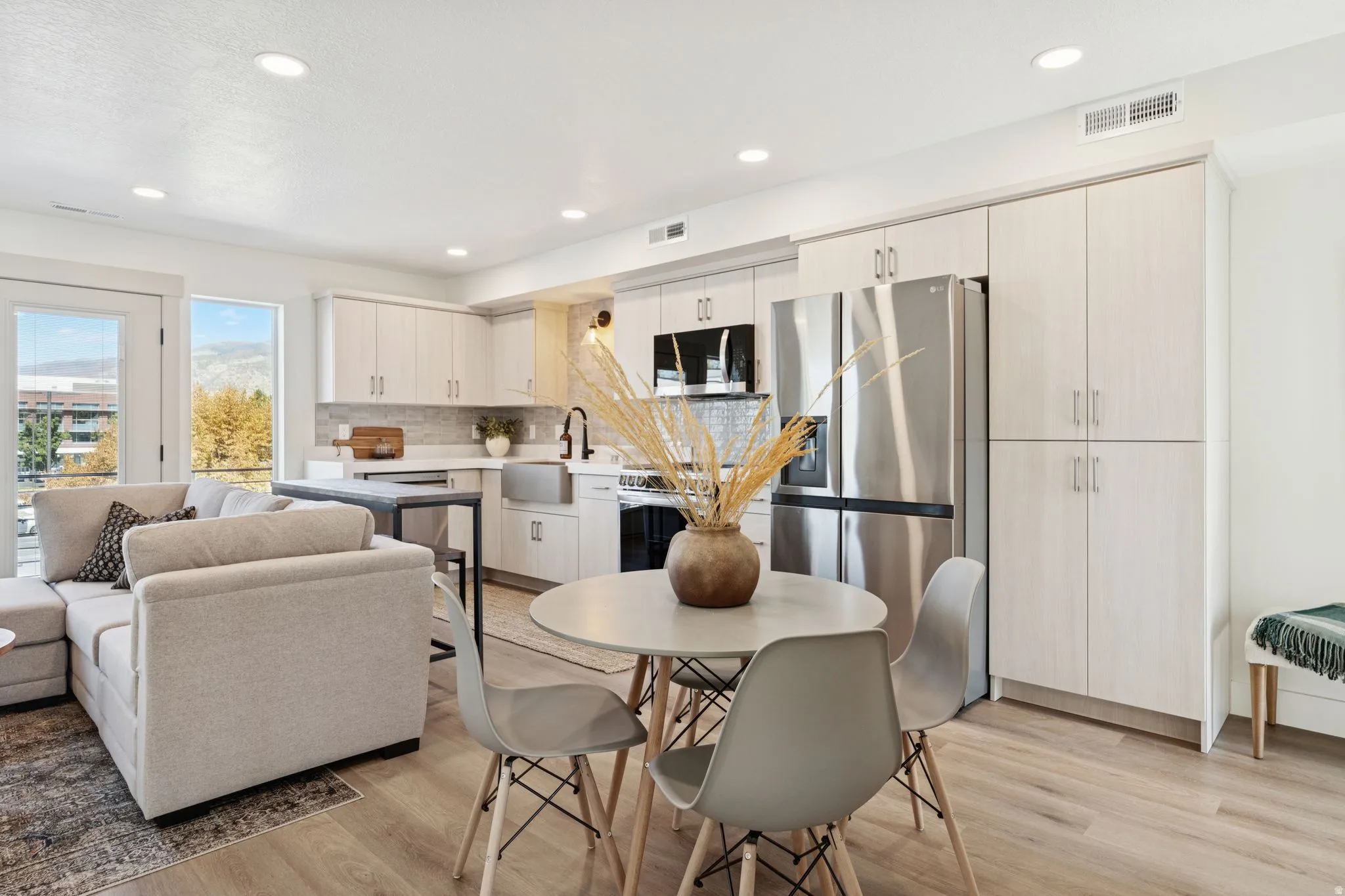 Kitchen with stainless steel appliances, light countertops, light wood finished floors, recessed lighting, and tasteful backsplash