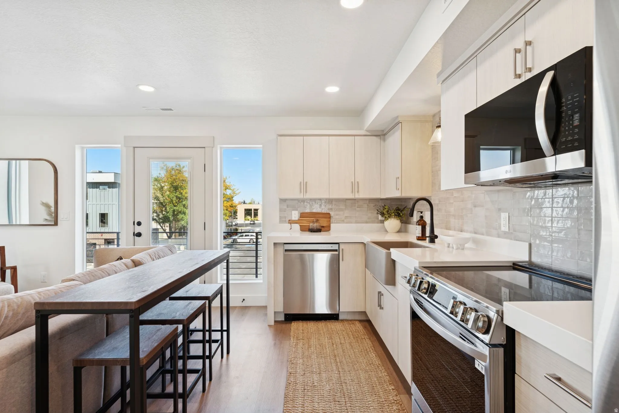Kitchen with stainless steel appliances, light wood-style flooring, light stone counters, backsplash, and modern cabinets