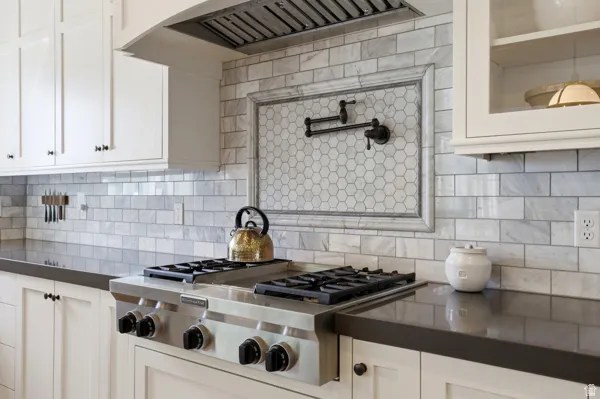 Kitchen with stainless steel gas cooktop, white cabinets, and decorative backsplash