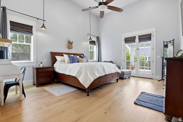 Bedroom featuring light wood finished floors, french doors, a high ceiling, a ceiling fan, and access to outside