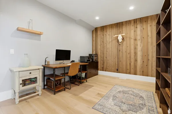 Office with wood walls, light wood-type flooring, recessed lighting, and an accent wall